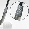 A silver-colored golf club head with a textured black and silver ferrule, shown next to a white golf ball and teeing stick, with a circular inset detail of the grip pattern.