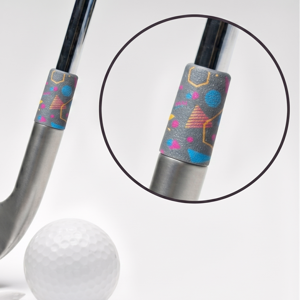 A silver golf club head with a colorful patterned ferrule, shown alongside a white golf ball, tees, and a circular inset close-up of the grip detail on a clean white background.