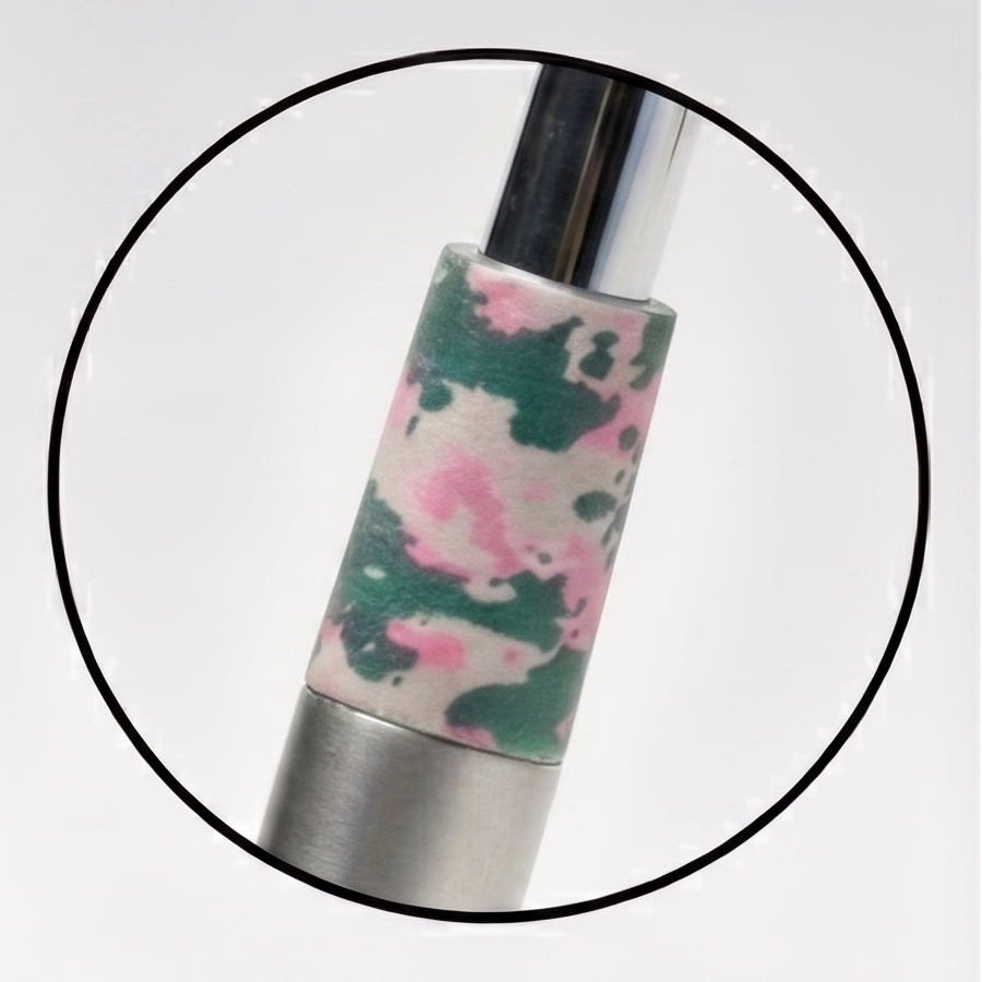A silver golf club head with a black shaft and a pink and green camouflage ferrule, shown alongside a white golf ball, tees, and a circular inset close-up of the camo ferrule detail.