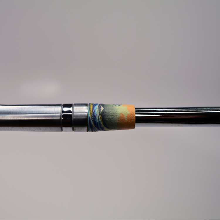 Close-up of a golf club iron shaft showing a colorful painted ferrule with blue, green, and orange details against a neutral gray background.