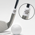 A silver golf club shown on a white background with a white golf ball, tees, and a circular inset highlighting a customizable white ferrule with the text 'YOUR DESIGN HERE'.