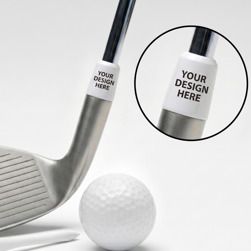A silver golf club shown on a white background with a white golf ball, tees, and a circular inset highlighting a customizable white ferrule with the text 'YOUR DESIGN HERE'.
